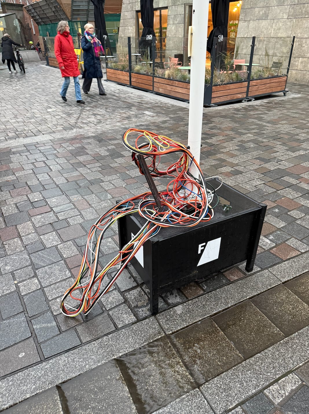 Cable Man installed in a city square, with pedestrians passing by